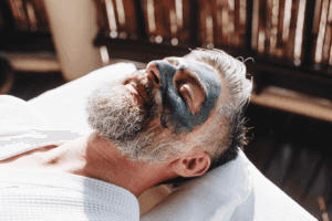 Bearded man getting a face mask treatment during a mens facial